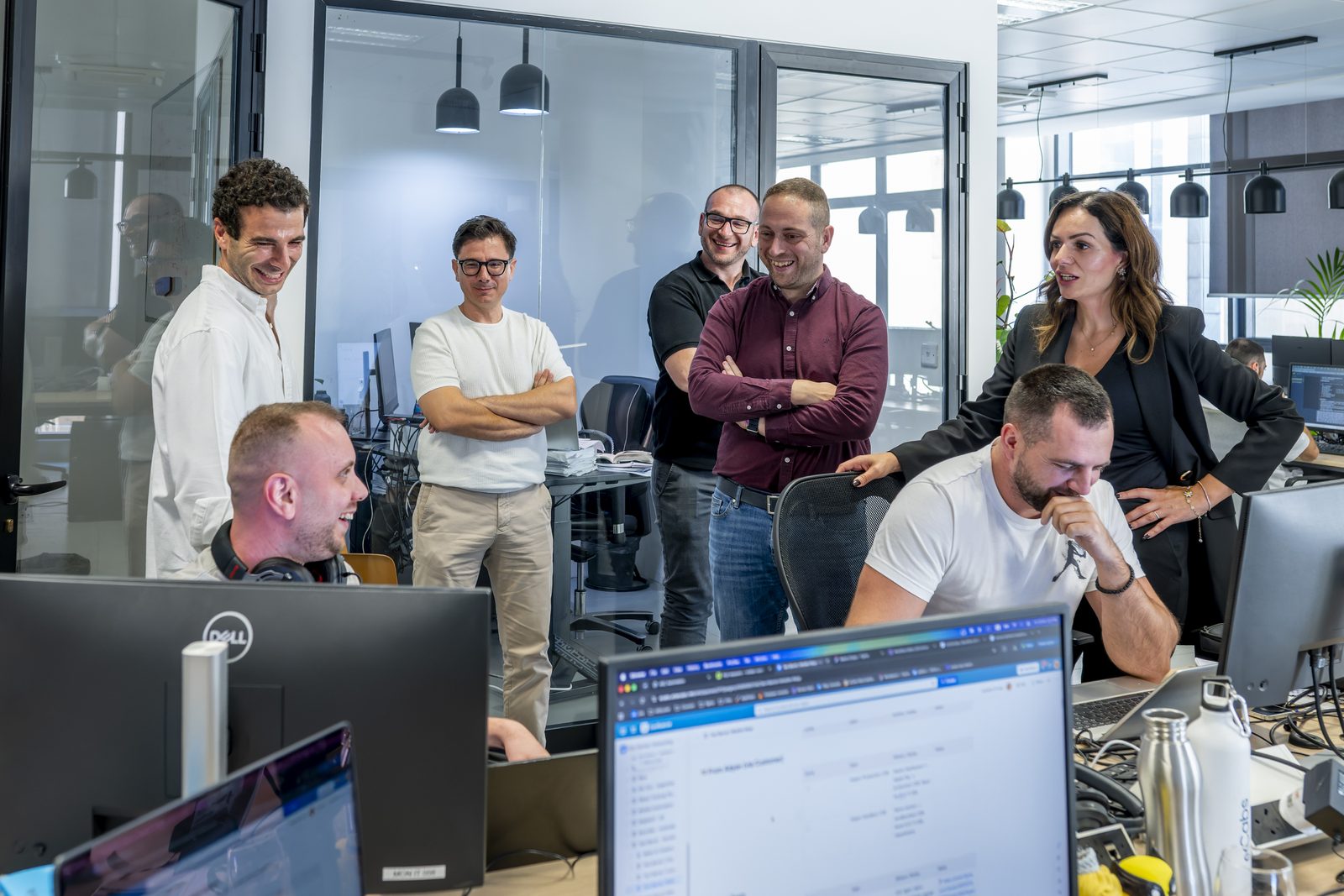 Visitors and the eCabs Technologies team gathered around a developer’s desk in the St Julian’s office